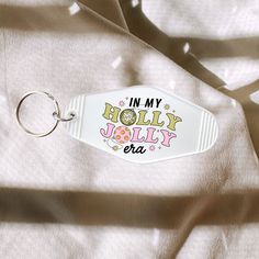 a white keychain with the words in my holly jolly era printed on it