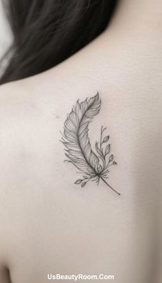 the back of a woman's shoulder with a feather tattoo on it