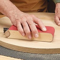 a person using a sanding block on a wooden table