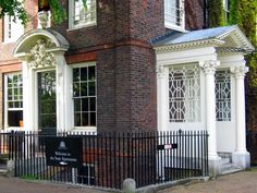 an old brick building with white windows and iron fence around the front entrance to it