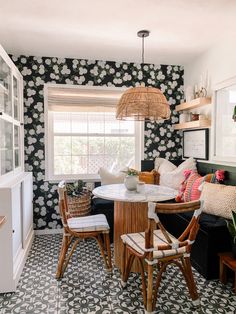 a dining room table and chairs in front of a window with flowers on the wall