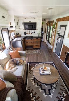 a living room filled with furniture and a dog laying on top of a couch next to a table