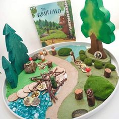 a tray with a book and some fake trees on it, along with other items