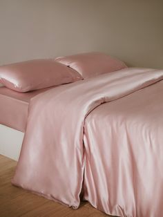 a bed with pink sheets and pillows on it