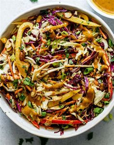 a white bowl filled with coleslaw, carrots and other veggies