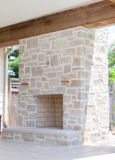 an outdoor fireplace is built into the side of a house with wood beams and brick