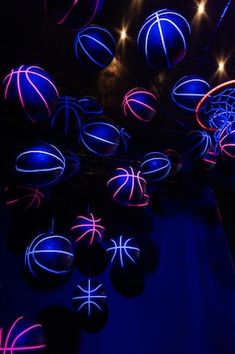 several basketballs are lit up in the dark with blue and pink lights around them