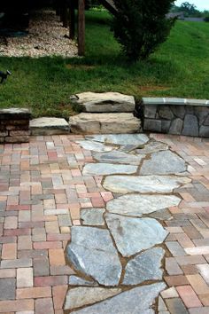 a brick patio with stone steps and grass in the background