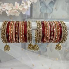 several bracelets are displayed on a stand with flowers in the backgrouf