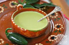 a small bowl filled with green liquid on top of a brown and orange saucer