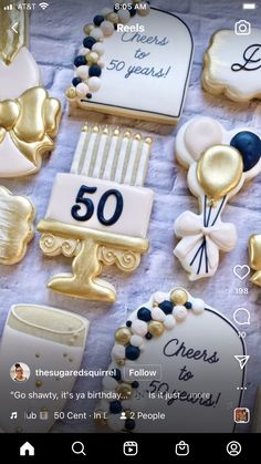 a table topped with lots of cookies covered in gold and white frosted icing