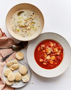 two bowls of soup and crackers on a white table with pink napkins next to them