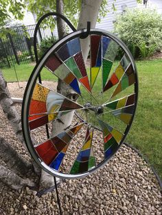 a wheel that is sitting on the ground next to a tree and some rocks in front of it