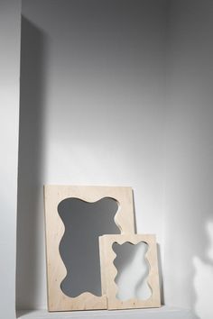 two wooden frames sitting on top of a white shelf next to a shadow cast object