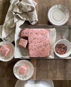 a cake with pink frosting and sprinkles sitting on top of a pan