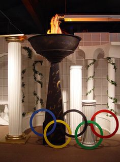 the olympic rings are on display in front of an ornate fountain with flames coming out of it