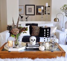 a living room filled with white furniture and lots of decor on top of a coffee table