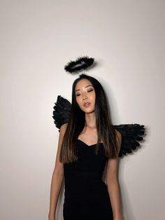 a woman in a black dress with angel wings on her head and long dark hair