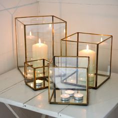 three glass cubes filled with candles sitting on top of a white countertop next to each other