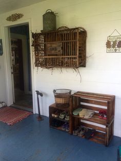 a wooden bench sitting next to a white wall with shoes on it and a birdcage hanging from the ceiling