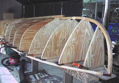 several wooden canoes are lined up in a shed