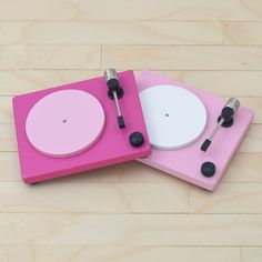 two pink and white turntables sitting on top of a wooden floor next to each other