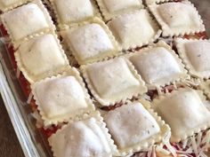 an uncooked casserole dish filled with ravioli and meat sauces