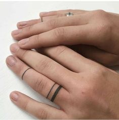 two hands with wedding rings on their fingers, one is black and the other is white