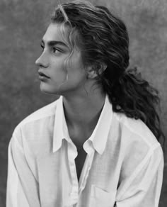 a black and white photo of a woman with long hair wearing a button up shirt