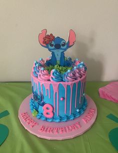 the birthday cake is decorated with blue icing and pink frosting, including an image of stitch