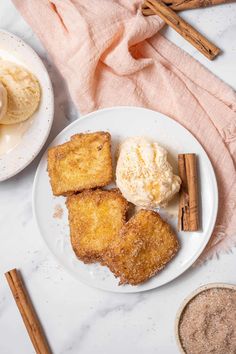 three pieces of bread on a plate with ice cream and cinnamon sticks next to it