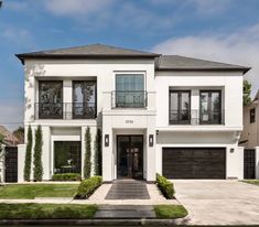 a white two story house with black garage doors