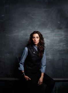 a woman standing in front of a chalkboard with her hands on her hips and looking at the camera