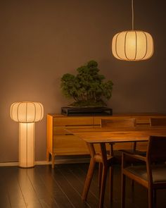 a table with two lamps on top of it next to a wooden dresser and chair