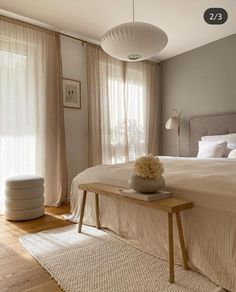 a bed room with a neatly made bed next to a window covered in sheer curtains