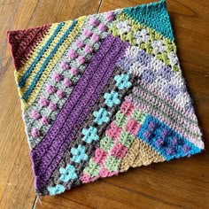 a multicolored crocheted dishcloth sitting on top of a wooden floor