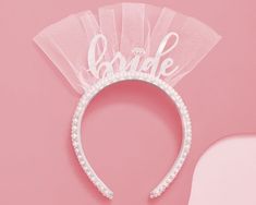 the bride headband is made with pearls and tulle on top of a pink background