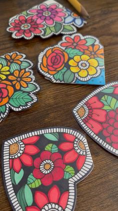 four colorful flowers are on the table next to a pencil and some paper cut outs