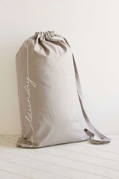 a gray bag sitting on top of a white floor next to a wooden floor and wall