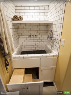 a bathroom with white tile and wooden drawers