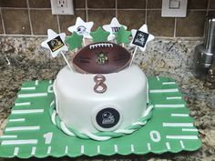 a football themed birthday cake on top of a green tablecloth with white frosting