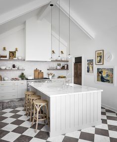 a kitchen with checkered flooring and white cabinets is pictured in this image, there are three stools at the center of the island