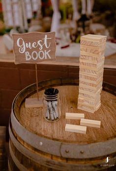 a wooden block tower sitting on top of a barrel next to a sign that says guest book