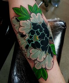 a woman's arm with a flower tattoo on it and green leaves in the center