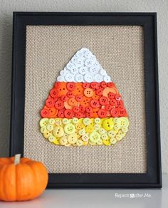 an orange pumpkin sitting next to a black frame with buttons on it and a button art piece