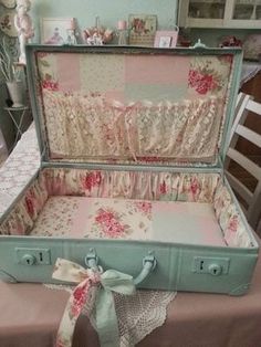 an open suitcase sitting on top of a table next to a pink and white chair