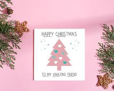 a pink christmas card with a tree on the front and hearts in the middle that says happy christmas to my amazing friend