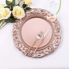 there is a pink plate with a fork and knife on it next to some flowers