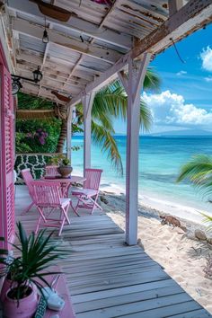 a porch with pink chairs and palm trees on the beach