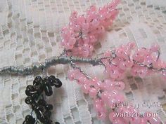 two pink and black beads are attached to some metal wire on a white lace surface